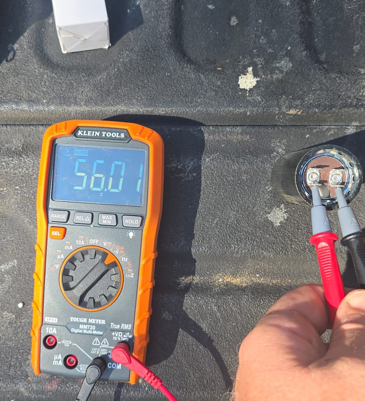 Replacement garage door opener capacitor being tested with a multimeter