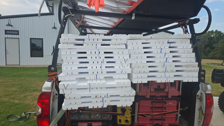 Stack of vinyl-backed insulation panels loaded in a StraightShot Overhead work truck, marked for each door section