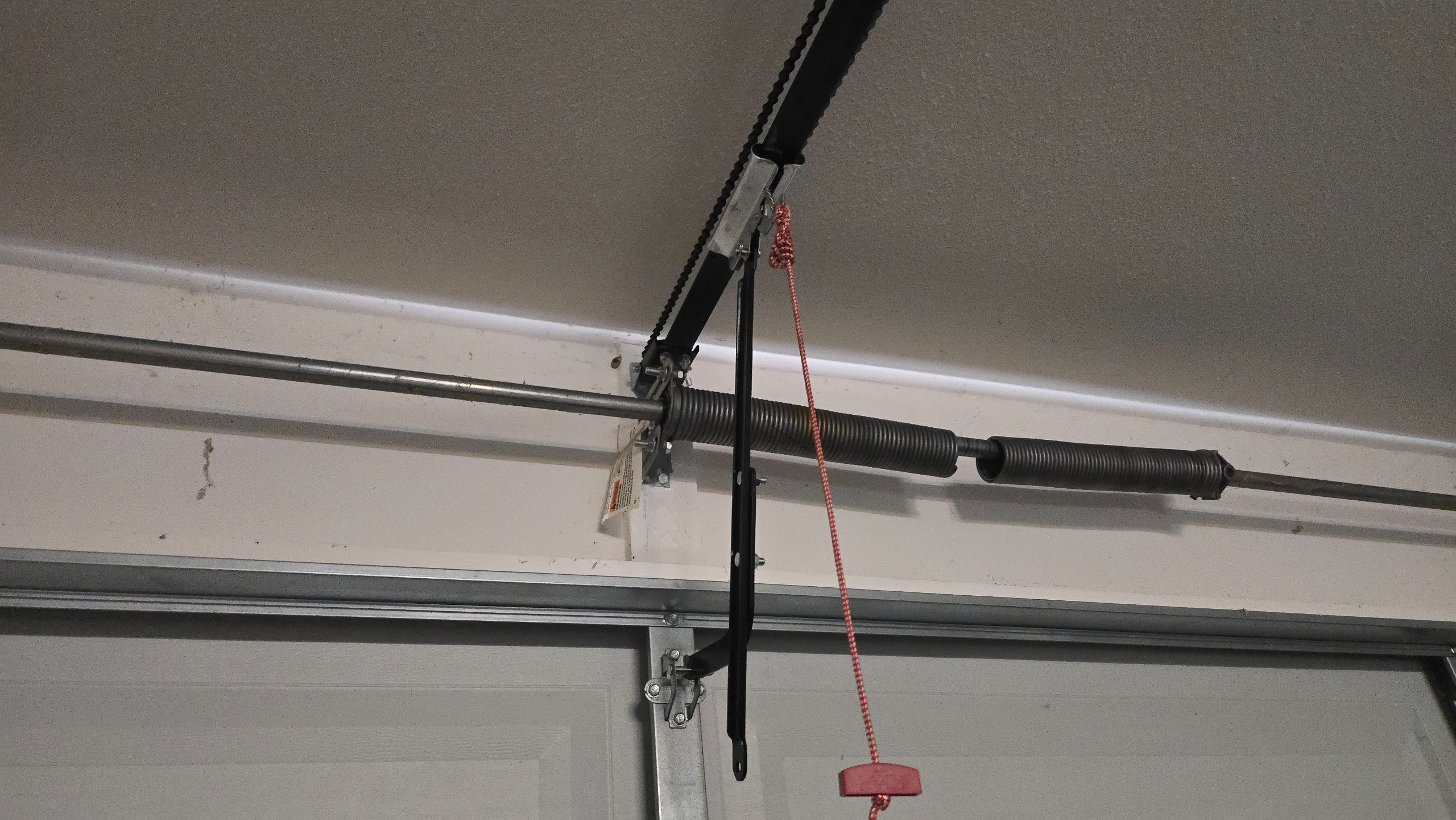 Broken torsion spring with a visible gap above the closed garage door in Tyler, TX