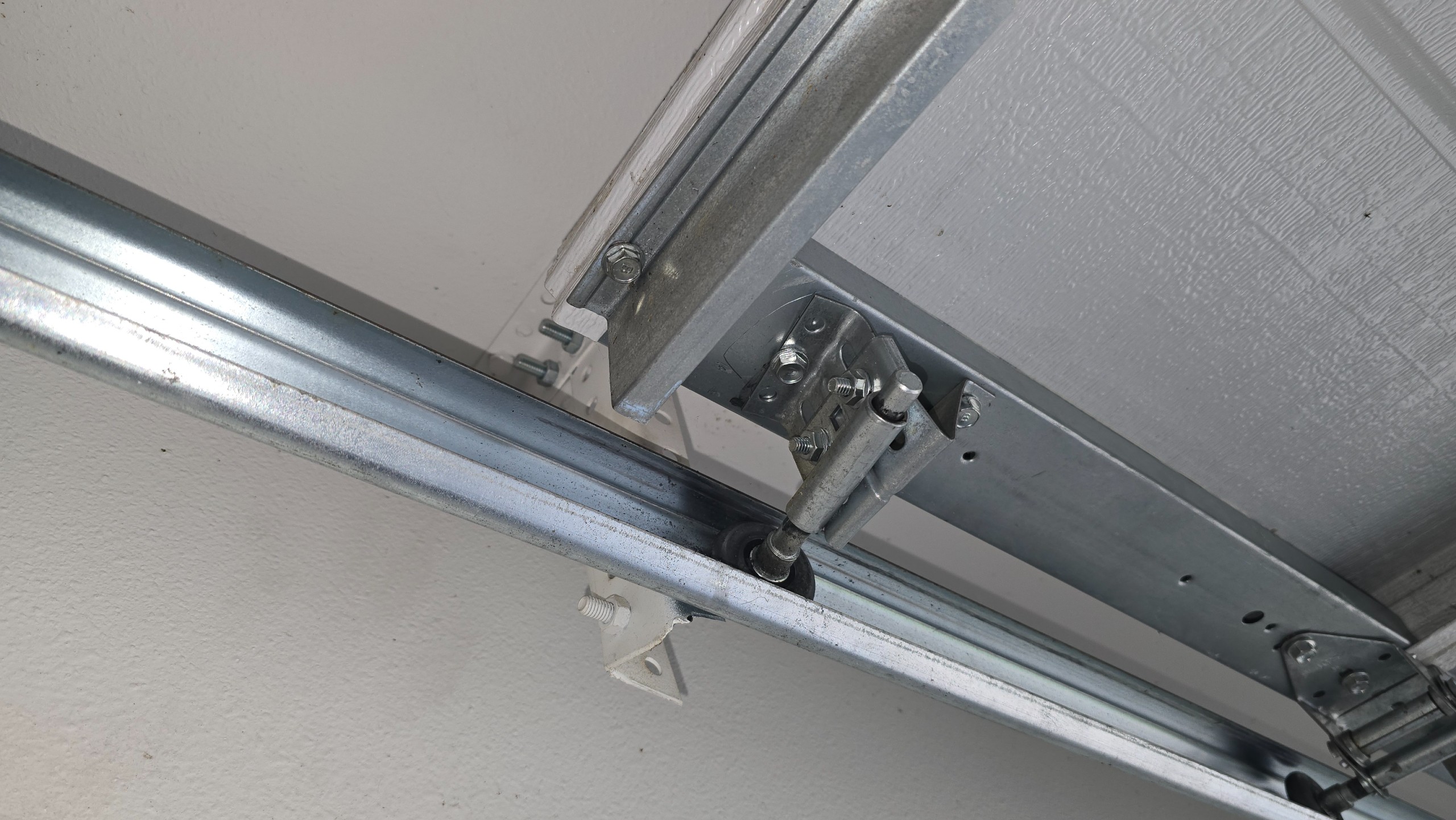 Top roller bracket and mounting bolts with the garage door raised in Tyler, TX