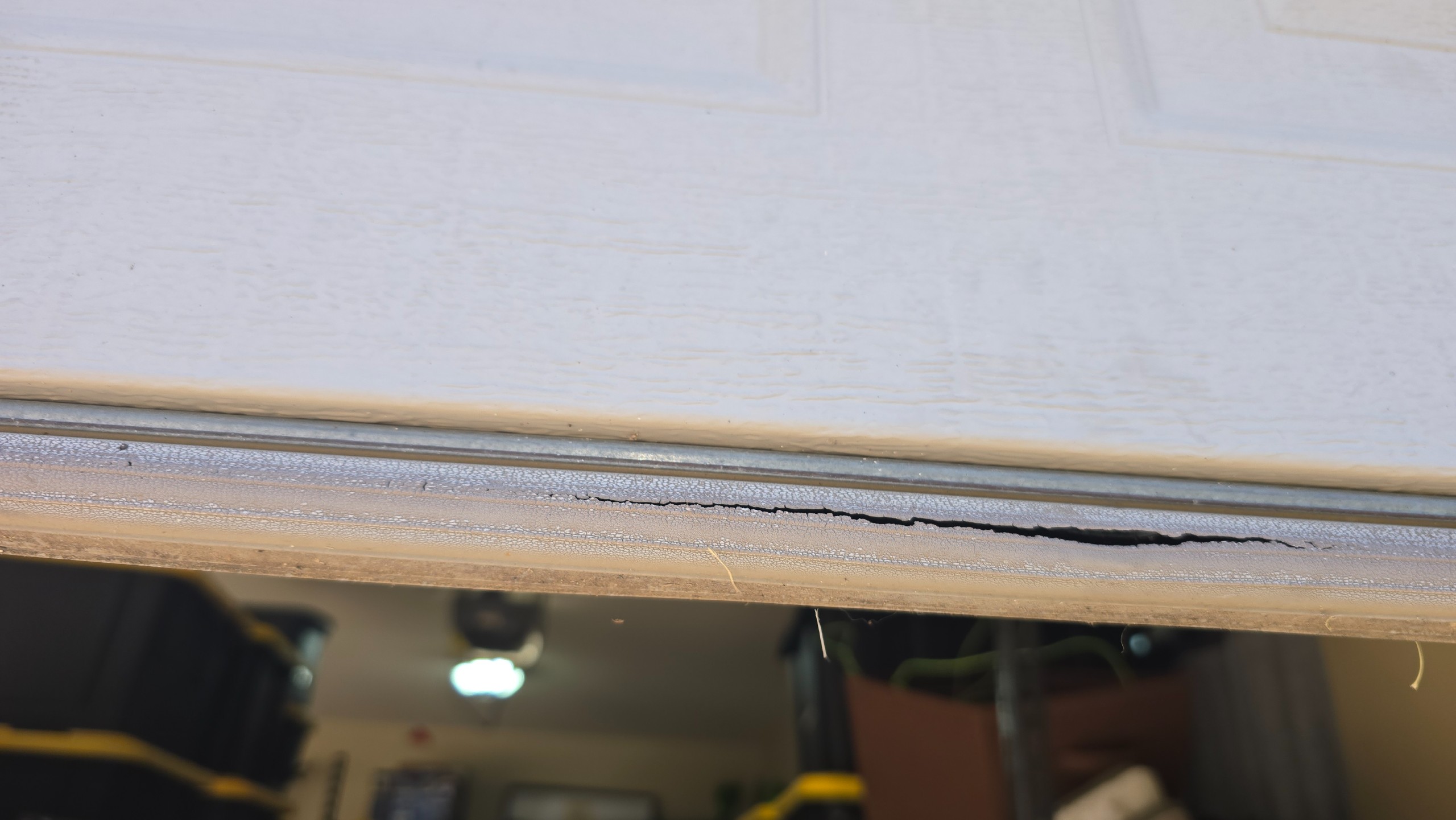 Long crack in the bottom weather seal beneath a garage door panel in Tyler, TX