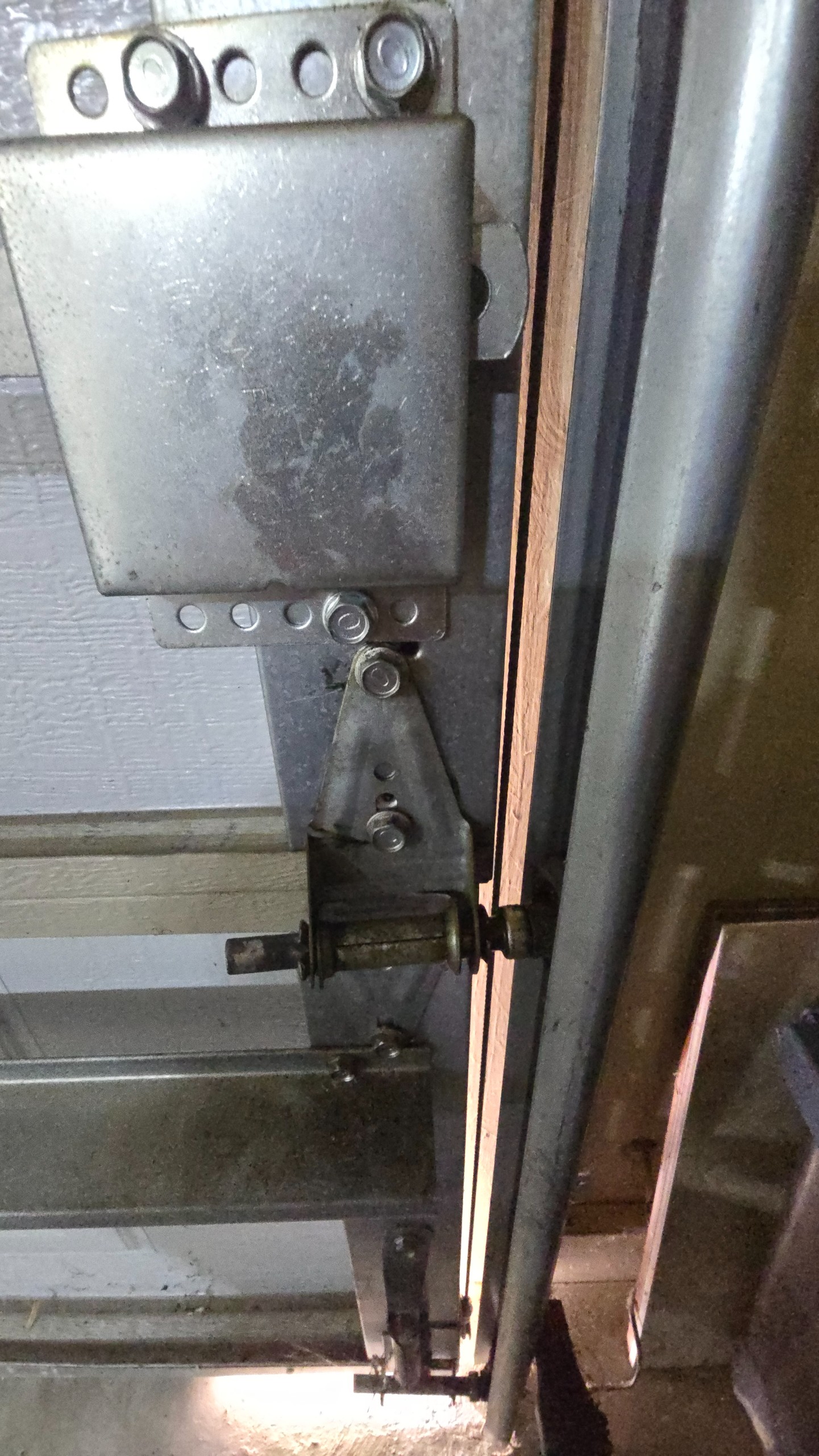 Broken garage door hinge beside the roller and vertical track in Tyler, TX